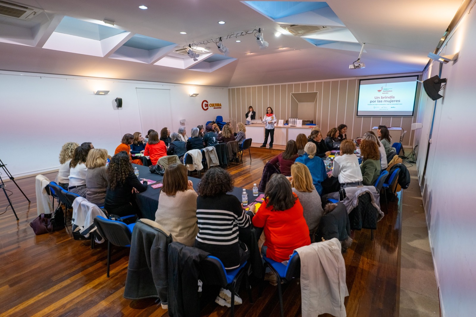 Encuentro de BrindisMujer con mujeres de distintas edades reunidas en varias mesas